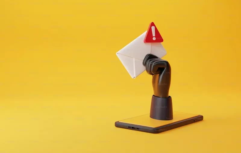 A smartphone displays a raised fist holding an envelope with an exclamation mark symbol against a yellow background, highlighting the issue of email blacklists.